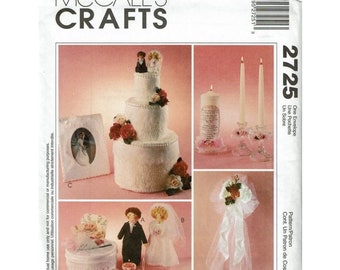 May include: A wedding themed craft pattern featuring a three-tiered cake, a pair of wedding figurines, a candle holder with a candle, a pair of candlesticks with candles, and a wedding bouquet. The pattern is from McCall's Crafts and is number 2725.