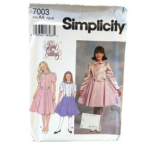 Puede incluir: Patrón de costura Simplicity número 7003 para vestidos de niña en tallas 7, 8 y 10. El patrón incluye tres estilos de vestidos diferentes: un vestido rosa con cuello blanco y mangas abullonadas, un vestido morado con cuello blanco y mangas cortas, y un vestido rosa con una chaqueta a cuadros. El patrón forma parte de la colección "Rare Editions".