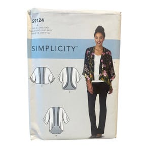 Könnte beinhalten: Eine Simplicity S9124 Schnittmusterhülle mit einer schwarzen Kimono-Jacke mit Blumenmuster, getragen über einem weißen Oberteil und einer dunklen Hose. Die Hülle zeigt technische Strichzeichnungen von drei Varianten des Jackendesigns.