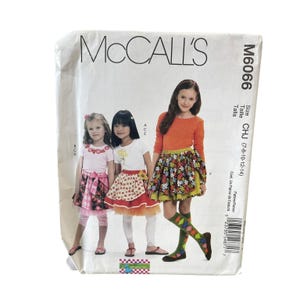 May include: A white ceramic mug with a black handle and the text "But First, Coffee" in a black, handwritten-style font. The mug is on a white surface.