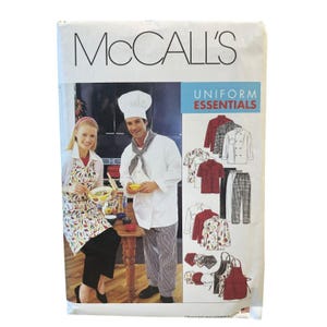 May include: A McCall's Uniform Essentials sewing pattern envelope featuring illustrations of chef coats, pants, aprons, and hats. The cover displays a photograph of two individuals in kitchen attire, with text reading McCall's and Uniform Essentials.