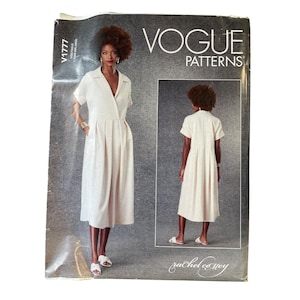 Op de afbeelding: Vogue Patterns naaipatroon met een vrouw in een lichtgekleurde jurk met korte mouwen en een kraag. Het patroon bevat voor- en achteraanzichten. De tekst "VOGUE PATTERNS" is zichtbaar.