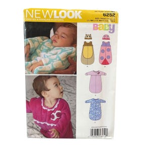 Könnte beinhalten: New Look 6252 Babyschnittmuster-Umschlag mit Illustrationen von vier Schlafsack-Designs, darunter ein Eulen- und Marienkäfer-Motiv. Die Verpackung zeigt Fotos von Säuglingen, die einen hellblauen Schlafsack mit Muster und einen magentafarbenen Fleece-Schlafanzug tragen.