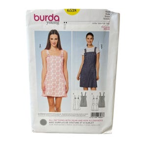 Könnte beinhalten: Ein Burda Young Schnittmuster für Kleider, Nummer 6538, mit zwei Kleiderdesigns. Eines ist ein rosa-weiß gemustertes Kleid, das andere ein Kleid im Jeans-Stil. Das Muster enthält die Größen EUR 32-44 und US 6-18.