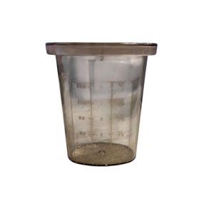 Puede incluir: Un vaso medidor de plástico transparente con un borde ancho y un cuerpo ligeramente cónico. El vaso tiene marcas de medición en mililitros y fracciones de taza. Está diseñado para medir líquidos y tiene una capacidad de 150 ml.