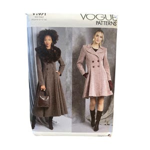 Op de afbeelding: Vogue Patterns naaipatroonpakket met twee jassenontwerpen. Het pakket toont een lange, bruine jas met een imitatiebontkraag en een kortere, roze jas. Het pakket heeft de tekst "V1971" en "VOGUE PATTERNS".