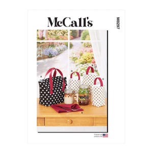 Könnte beinhalten: Ein McCall's-Schnittmuster mit verschiedenen Stofftaschen mit roten Griffen und weißen Tupfen auf schwarzem Hintergrund. Das Bild zeigt auch Gläser mit Essen und eine rote Serviette auf einem Holztisch.