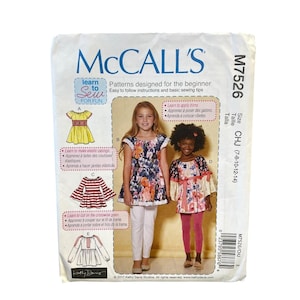 May include: McCall's sewing pattern for girls' dresses and tops. The pattern includes instructions for beginner sewers. The image shows two girls wearing the finished garments. The pattern size is CHJ (7-8-10-12-14).