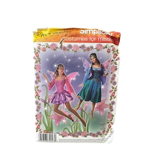 May include: A vintage Simplicity sewing pattern for costumes for misses. The package features illustrations of two women in fairy costumes with pink and blue wings. The background has flowers and stars. The package is yellowed with age.