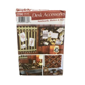 May include: A Simplicity pattern for desk accessories, including note boards and blotters. The image shows examples of the finished products, such as a striped note board with attached cards and a floral-patterned blotter. The pattern number is 5196.