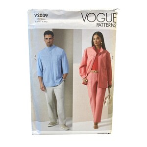 May include: Vogue Patterns sewing pattern envelope showing a man in a light blue shirt and trousers, and a woman in a pink suit. The envelope has the text "V2039" and "VOGUE PATTERNS". The size range is indicated as S-M-L-XL-XXL.
