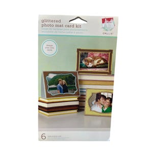 Puede incluir: Un paquete de 6 kits de tarjetas para fotos con tapete de fotos con brillo. El paquete presenta una sección de diseño de tus propias tarjetas y una foto de un gato durmiendo en un marco marrón. El paquete está etiquetado como "kit de tarjetas para fotos con tapete de fotos con brillo" y "CREATE".