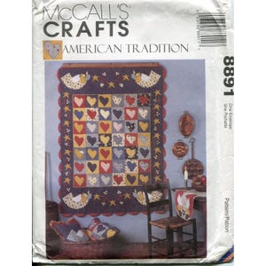 May include: McCall's Crafts pattern for an American Tradition quilt. The quilt features a grid of heart-shaped blocks in various colors, framed by a scalloped edge and bird and star accents. The pattern includes the number 8891.
