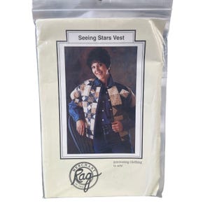 May include: A sewing pattern package titled Seeing Stars Vest by Merchant Rag. The package features a photograph of a person wearing a quilted vest with a star pattern in shades of tan, brown, and blue, layered over a dark blue button-down shirt.