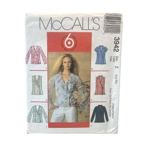 May include: A McCall's 3942 sewing pattern envelope featuring a central photograph of a person wearing a light blue floral wrap top. The envelope displays six different garment variations labeled A through F, including long and short sleeve options.