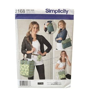 May include: Simplicity sewing pattern 2168 for a crossbody bag and small pouch. The pattern features a paisley and dotted fabric design. The image shows the bag being worn by a person. The pattern is one size.