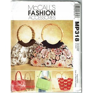 Op de afbeelding: Een patroonhoes van McCall's Fashion Accessories met verschillende handtassenontwerpen. De hoofdafbeelding toont twee handtassen met bamboe handvatten en bloemenstof. Andere ontwerpen omvatten draagtassen in rood, bruin en groen.