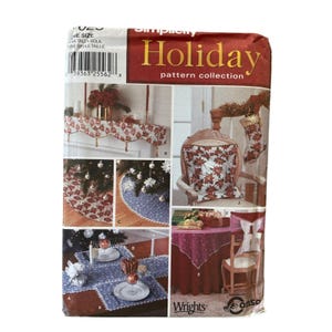 May include: A Simplicity Holiday pattern collection with festive sewing projects. The image shows a table runner, tree skirt, pillow, and table setting, all with holiday designs. The cover includes the text "Holiday pattern collection".