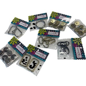 May include: A collection of various metal hardware pieces, including rings, clasps, and magnetic snaps, packaged in clear plastic bags. The packaging features a floral design with the text "everything Mary".