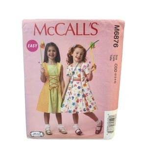 May include: A McCall's sewing pattern package featuring two young girls in dresses. The package is pink with the McCall's logo and the text "EASY". The pattern number is M6876, and the size is CDD (2-3-4-5).