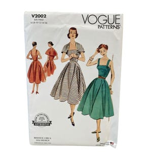 Puede incluir: Un paquete de patrones de costura Vogue Patterns con ilustraciones de vestidos vintage. El paquete muestra varios estilos de vestidos, incluyendo un vestido a rayas, un vestido verde y un vestido rojo. El paquete está etiquetado como "V2002" y "Reissue Circa 1952 Design."