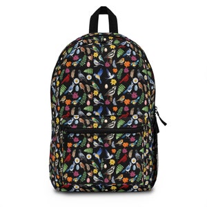 May include: Black backpack with a colorful pattern of birds and flowers. The birds are in various colors and poses, including flying, perched, and singing. The flowers are in shades of pink, red, yellow, and blue.