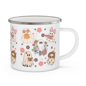 May include: A white enamel mug with a silver rim featuring a repeating pattern of cartoon ghosts, flowers, and books. The ghosts are depicted in various activities, including reading books, holding a pumpkin, and wearing hats or bows in soft pastel colors.