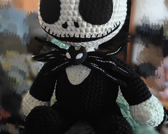 May include: A crocheted plush toy of Jack Skellington from the Nightmare Before Christmas. The toy is white with black eyes and a black mouth. It is wearing a black and white striped suit with a black bow tie.