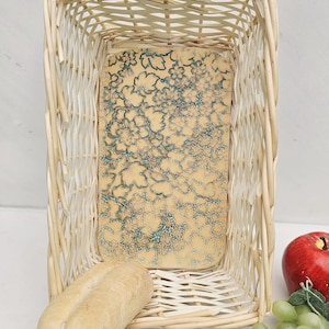 May include: A white wicker basket with a floral patterned liner. The basket is filled with bread and grapes.