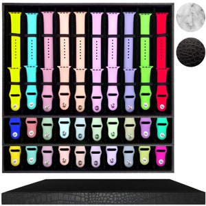 May include: A black velvet watch band storage box with three tiers. Each tier has 8 slots for storing watch bands. The box has a black crocodile embossed lid.