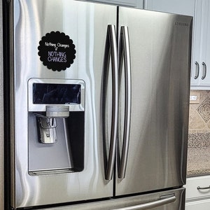 May include: A stainless steel refrigerator with a black chalkboard magnet that says "Nothing Changes if NOTHING CHANGES".