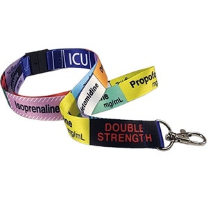 Op de afbeelding: Een kleurrijk koord met de woorden "ICU", "Isoprenaline", "Detomidine", "Propofol", "mg/mL" en "DOUBLE STRENGTH" erop gedrukt. Het koord heeft een zilveren clip.
