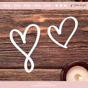May include: Two white hand-drawn hearts on a brown wooden background. The hearts are simple and slightly imperfect, giving them a rustic charm.