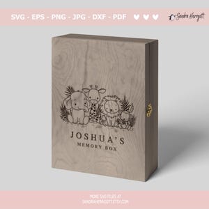 May include: A wooden box with a light brown finish. The box has a hinged lid and a brass latch. The front of the box is engraved with a design of a giraffe, elephant, lion, and monkey. The text "Joshua's Memory Box" is engraved below the design.