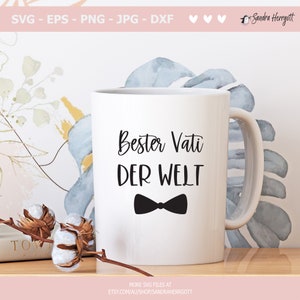 May include: White ceramic mug with a black bow tie and the text "Bester Vati DER WELT" in black.