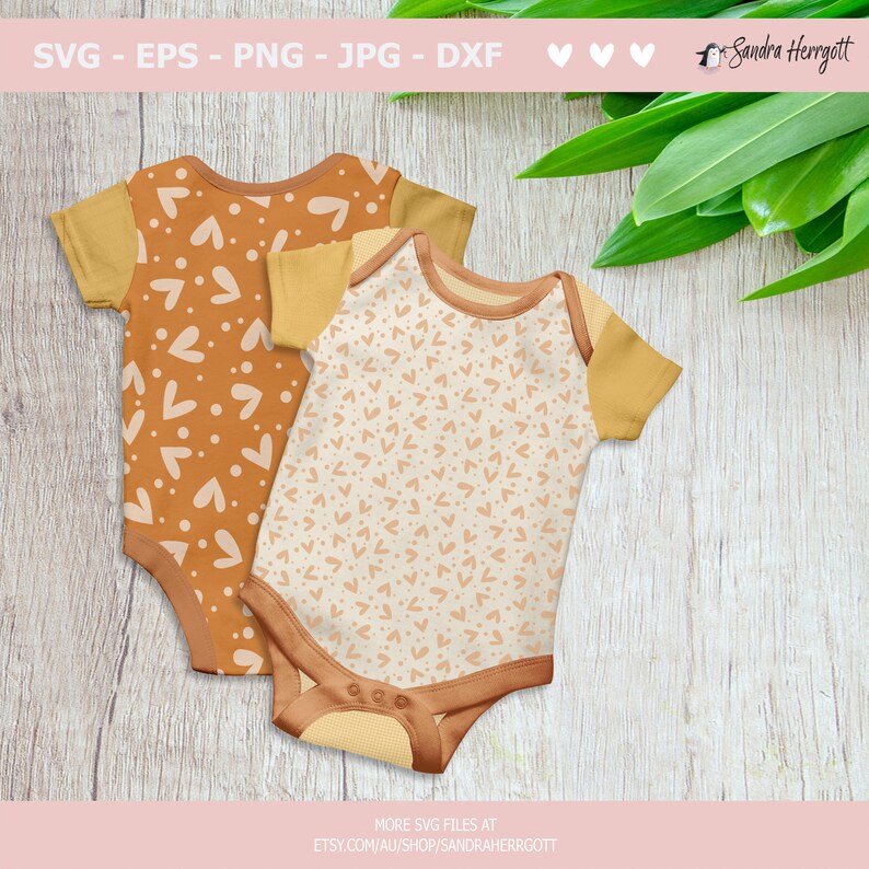 May include: Two baby onesies with a brown and white heart pattern. The onesies have yellow trim around the neck and sleeves.