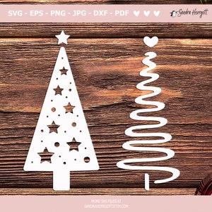May include: Two white Christmas tree cutouts on a wood background. The tree on the left has a star on top and is decorated with stars and dots. The tree on the right is a simple, wavy line with a heart on top.