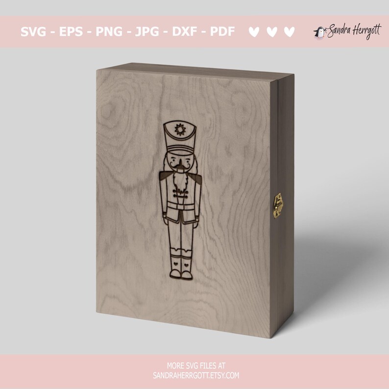 Może przedstawiać: Drewniana skrzynka z grawerowanym wzorem na froncie przedstawiającym łamacza orzech&oacute;w. Skrzynka ma złoty zamek i jest wykonana z jasnobrązowego drewna.