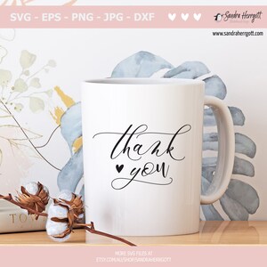 Puede incluir: Taza de cer&aacute;mica blanca con una inscripci&oacute;n en cursiva negra que dice "thank you" con un peque&ntilde;o s&iacute;mbolo de coraz&oacute;n antes de la palabra "you".