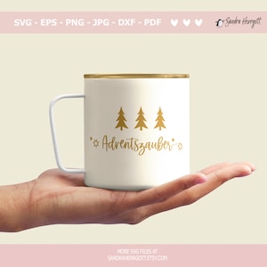 May include: A cream-coloured mug with a gold rim and white handle, decorated with gold fir trees and the word "Adventszauber". The mug is held in a hand. The image also includes the text "SVG - EPS - PNG - JPG - DXF - PDF" and "MORE SVG FILES AT SANDRAHERRGOTT.ETSY.COM".