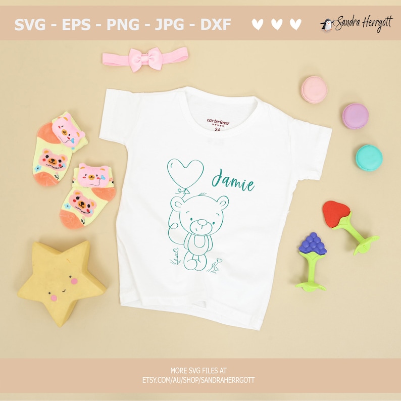 May include: A white baby onesie with a teal outline of a teddy bear holding a heart-shaped balloon. The onesie has the name "Jamie" written in teal script.