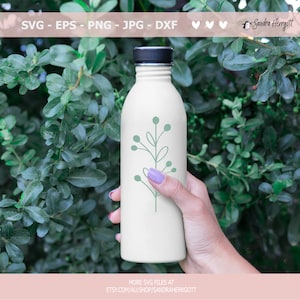 May include: A white water bottle with a green leafy branch design. The bottle is being held by a hand.