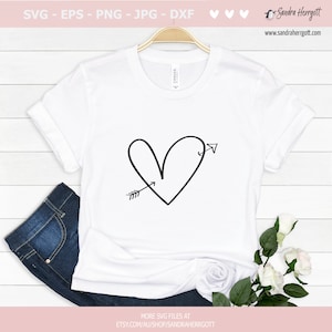 May include: A white t-shirt with a black hand-drawn heart with an arrow through it. The arrow is pointing to the left side of the heart.