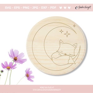 May include: A wood-toned circle with a line drawing of a fox curled up asleep on a crescent moon with two stars above. The image is suitable for crafting projects.