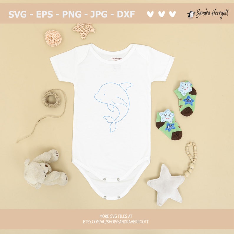 May include: A white baby onesie with a blue outline of a dolphin on the front. The onesie is surrounded by various baby items, including a star-shaped rattle, a pair of socks with stars, and a teddy bear.