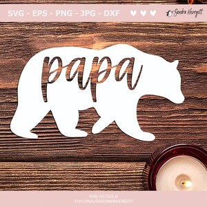 May include: A white bear silhouette with the word "papa" cut out in the center. The image includes text at the top indicating file types: SVG, EPS, PNG, JPG, and DXF. Additional text at the bottom directs viewers to an Etsy shop.