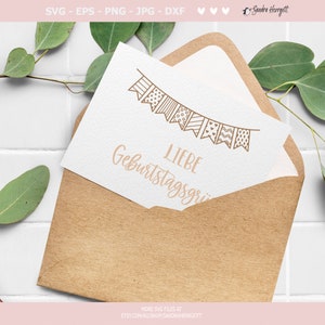 May include: A white card with a brown envelope. The card features a hand-drawn illustration of a string of bunting flags with various patterns. The text "LIEBE Geburtstagsgr" is written beneath the bunting.