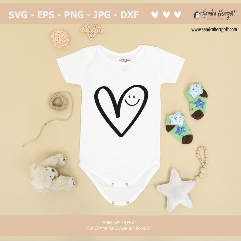 May include: White baby onesie with a black hand-drawn heart with a smiley face inside. The onesie is on a beige background with a teddy bear, a star, and a string of wooden beads.