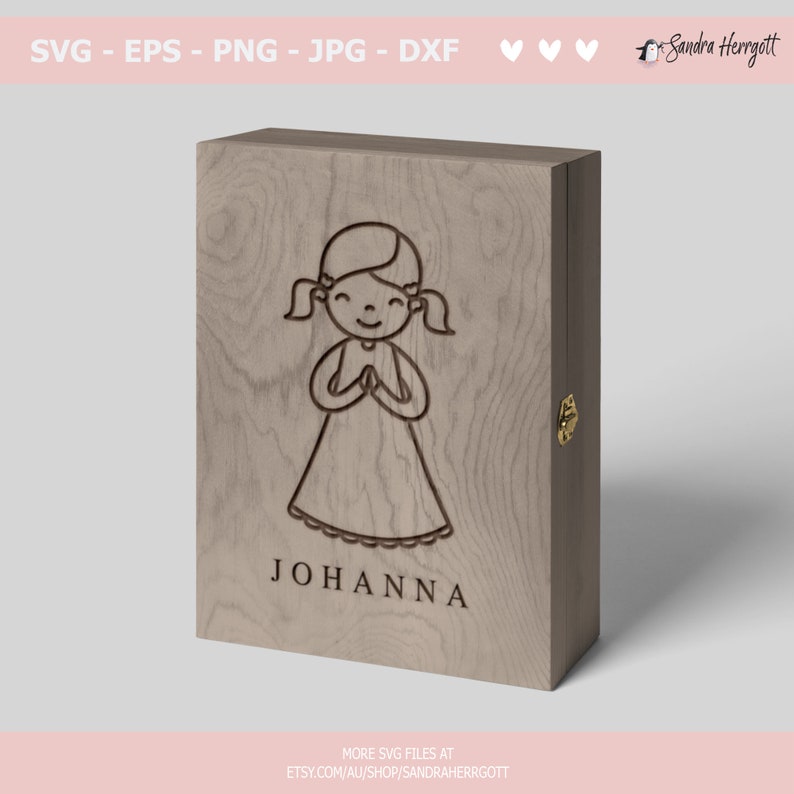 Peut inclure: Une bo&icirc;te en bois avec un couvercle &agrave; charni&egrave;re, pr&eacute;sentant un motif grav&eacute; au laser d'une fille avec des tresses, les mains jointes en pri&egrave;re. Le nom "JOHANNA" est grav&eacute; sous l'image.