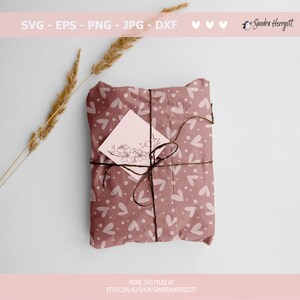 May include: A gift wrapped in brown paper with a white heart pattern. The paper is tied with twine and a small white card with a floral design is attached.